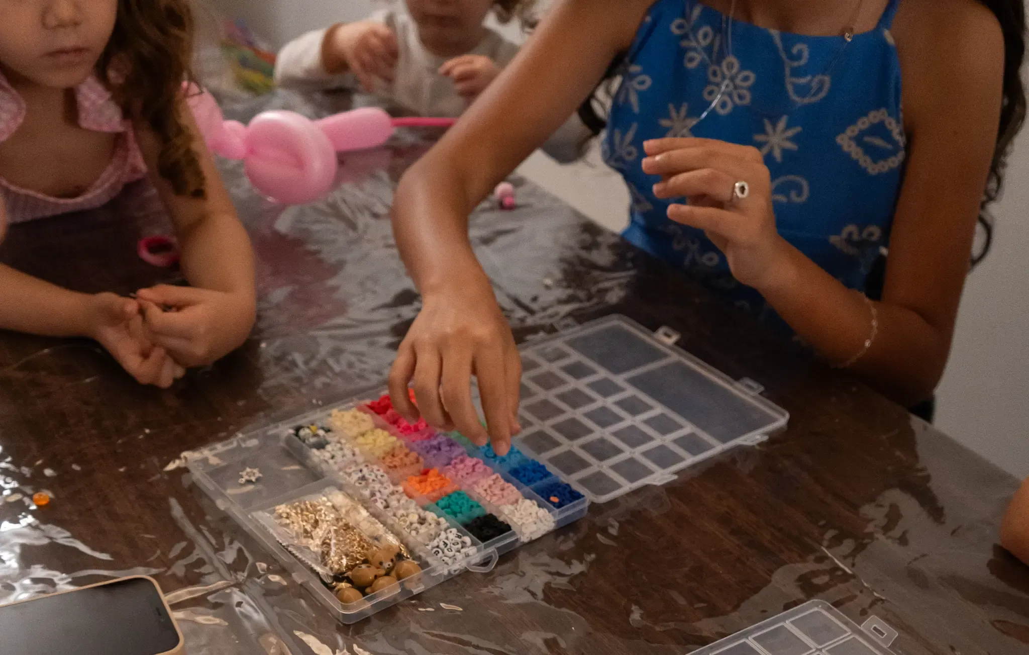 Crianças a escolher contas coloridas junto a um balão cor-de-rosa