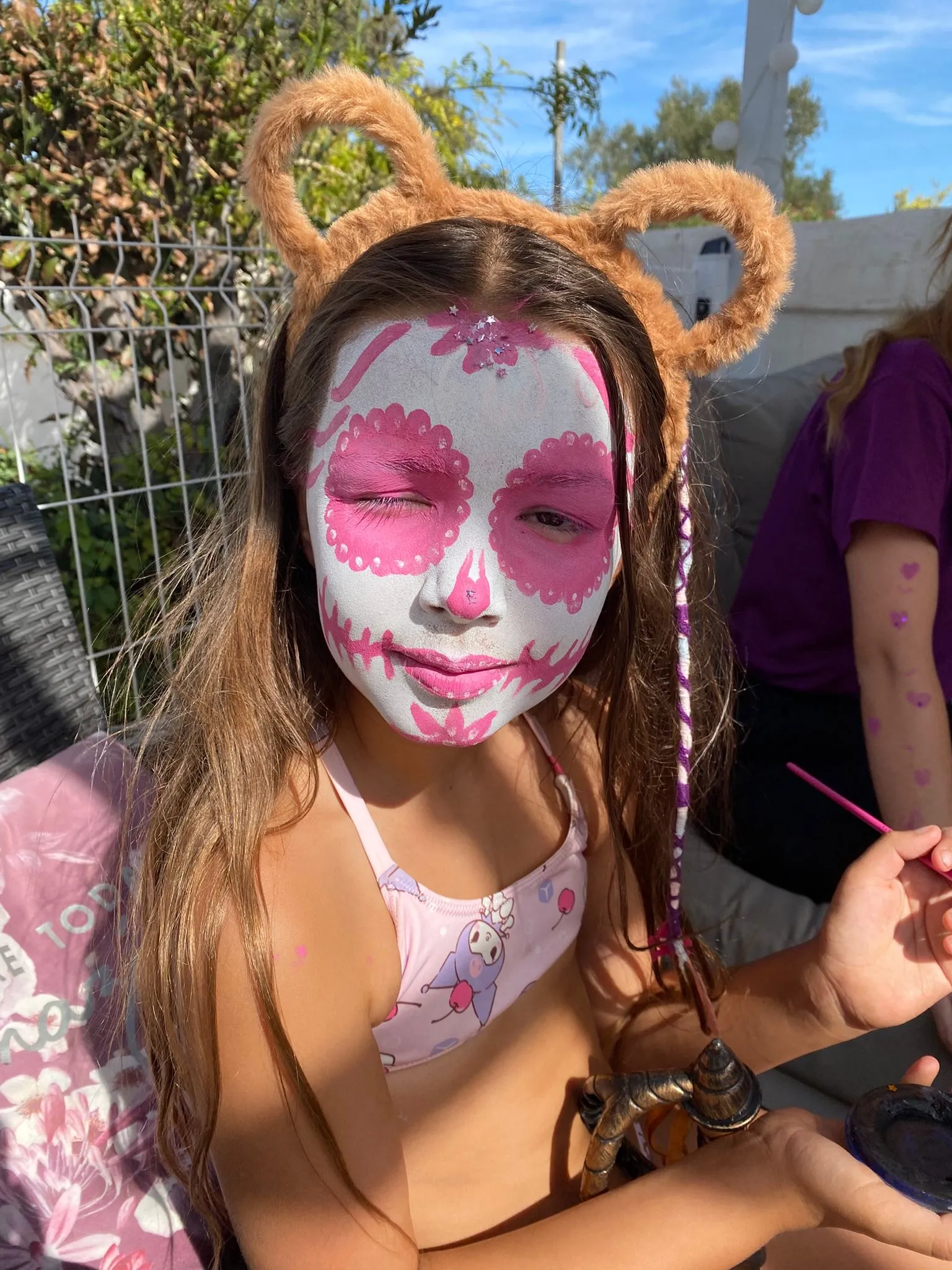 Menina com pintura facial artística colorida numa festa de aniversário
