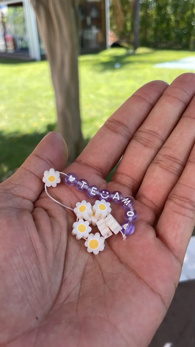 Pulseira artesanal com contas roxas e brancas e a mensagem Te Amo