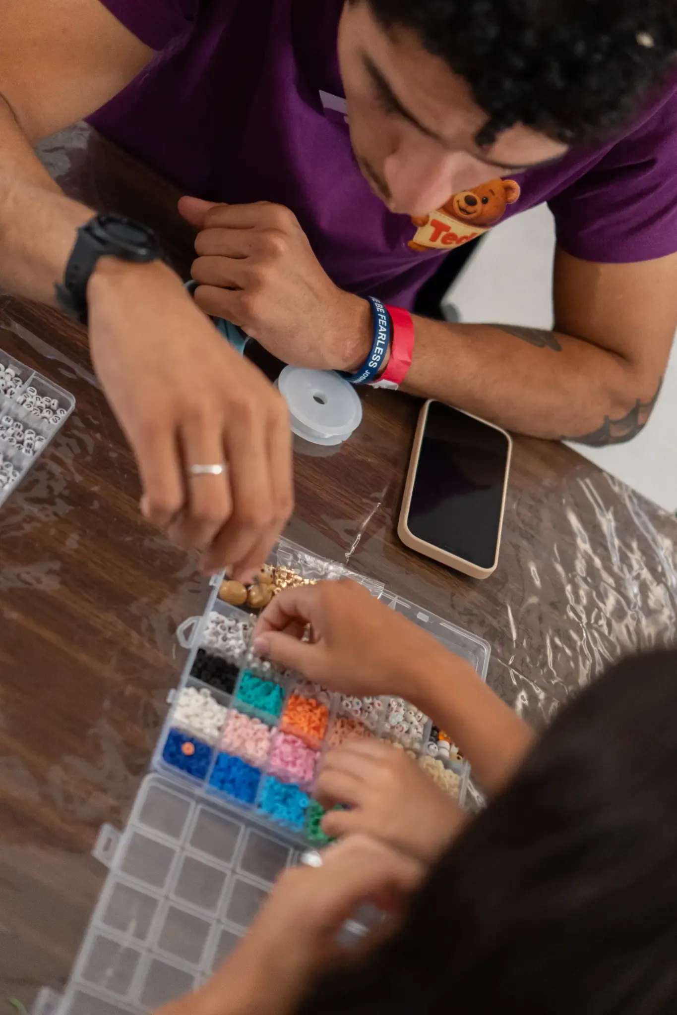Ted a fazer pulseiras com crianças numa oficina criativa